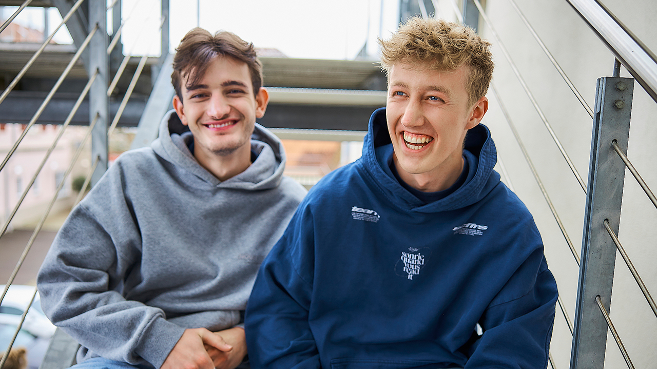 Zwei junge Mensschen sitzen auf einer Treppen und lachen
