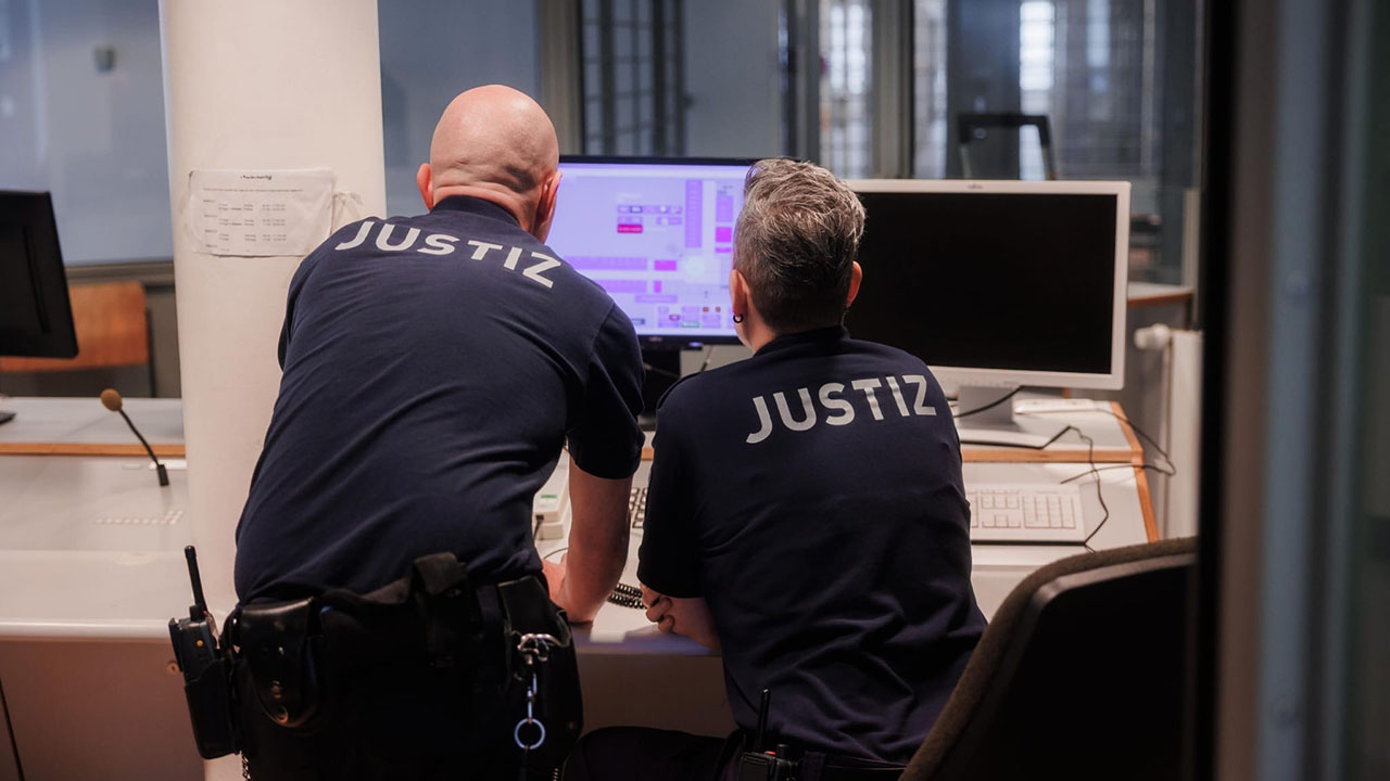 Das Bild zeigt zwei Mitarbeiter der JVA Cottbus-Dissenchen/MdJD Brandenburg an einem Computer.