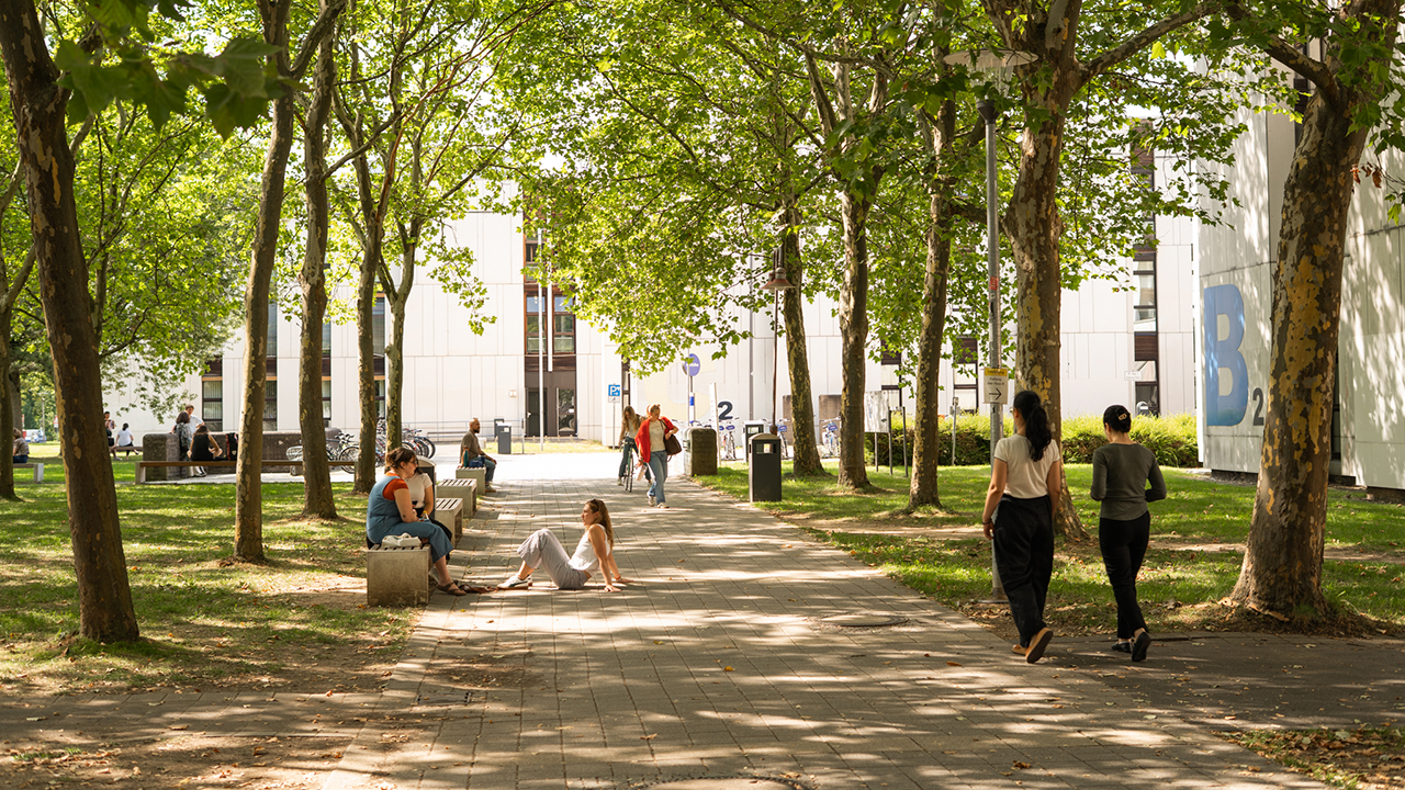 Das Bild zeigt den Campus der JLU mit einigen Studierenden.