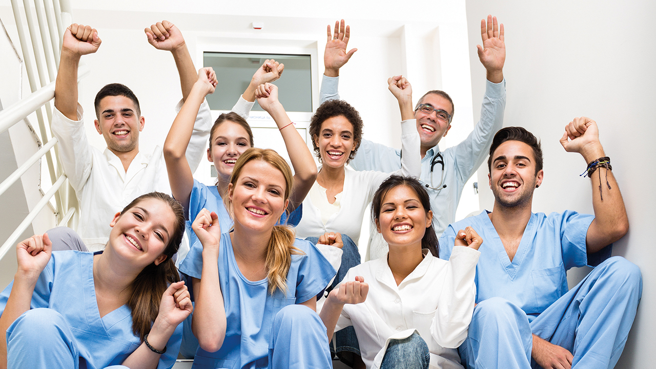 Gruppe Mitarbeitende, die freudig die Hände hochstrecken
