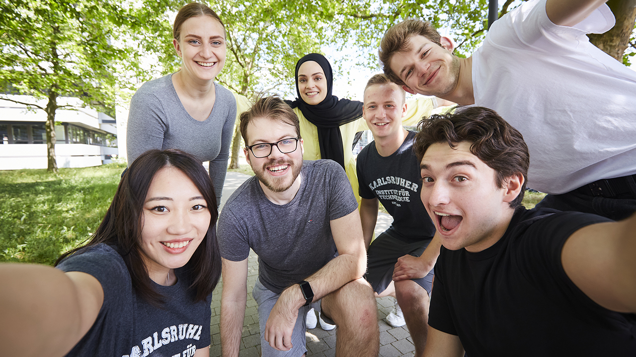 Das Bild zeigt eine Personengruppe die ein Selfie macht und die Kamera lächelt.
