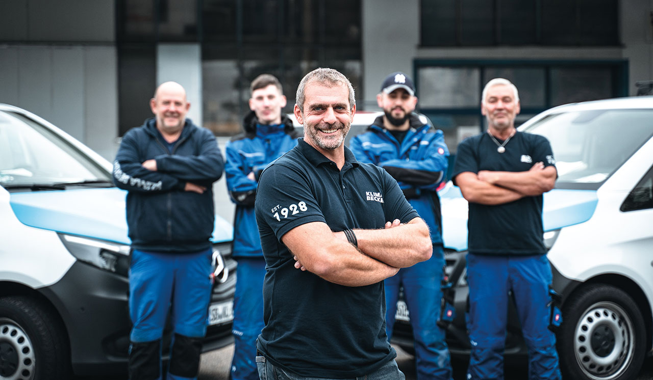 Gruppenbild, im Hintergrund stehen zwei Autos