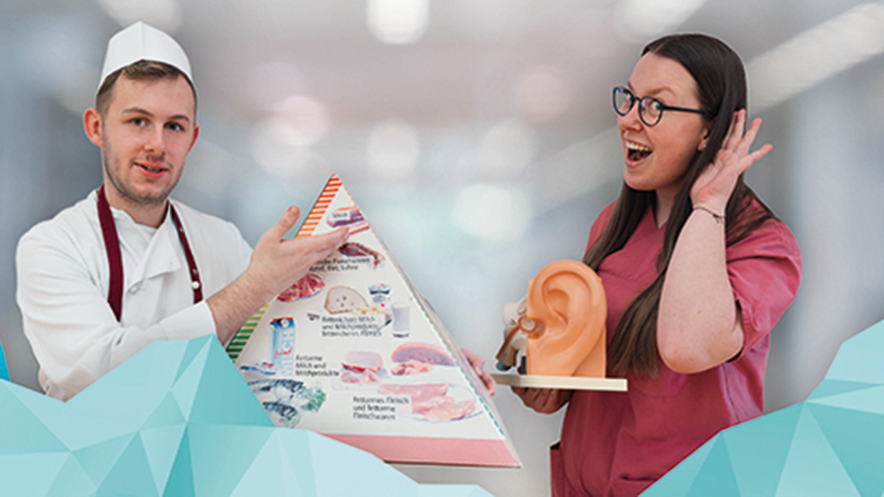 2 Mitarbeitende der Klinik Bavaria in Berufskleidung. Eine Person hält eine Ernährungspyramide in der Hand, die andere das Modell eines Ohres.