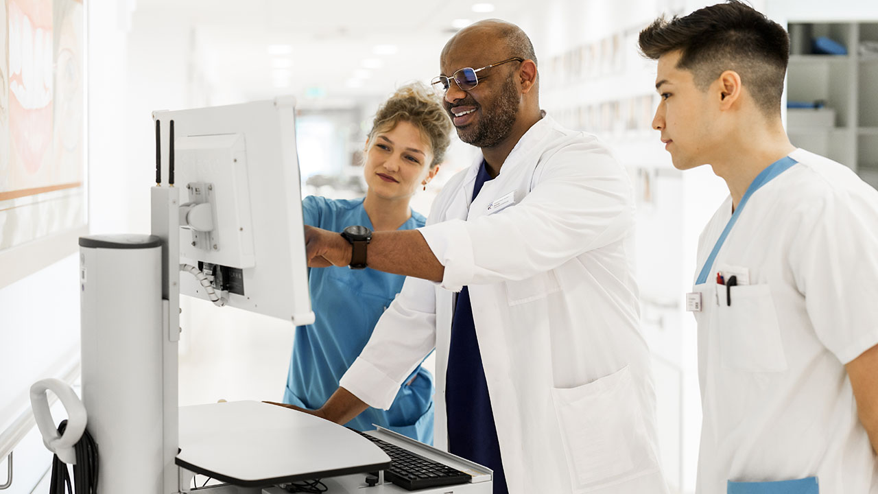 Ärzte und Pflegepersonal stehen vor einem Computer und lächeln.