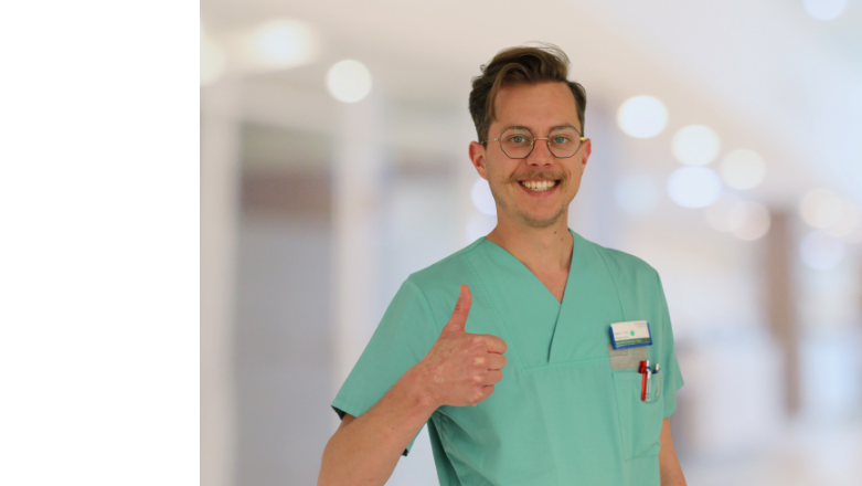 Mitarbeiter lacht in die Kamera und hält den Daumen hoch