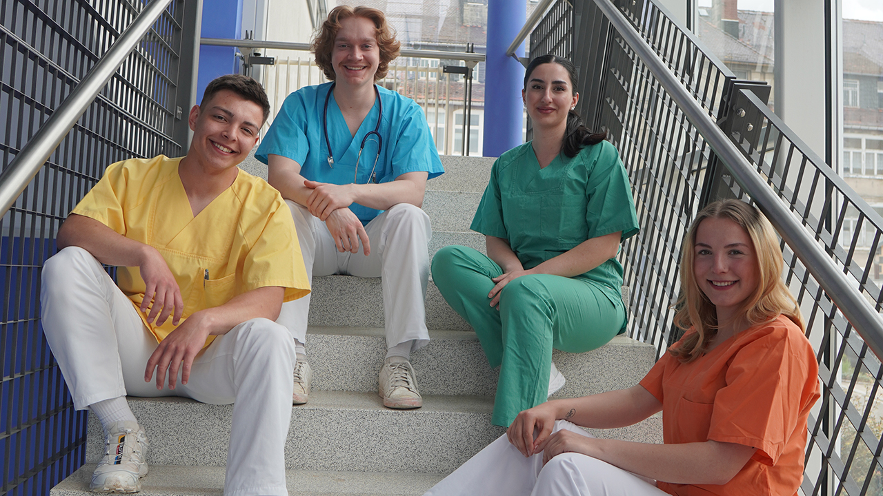 4 Mitarbeitende des Klinikum Mittweida sitzen locker auf einer Treppe.
