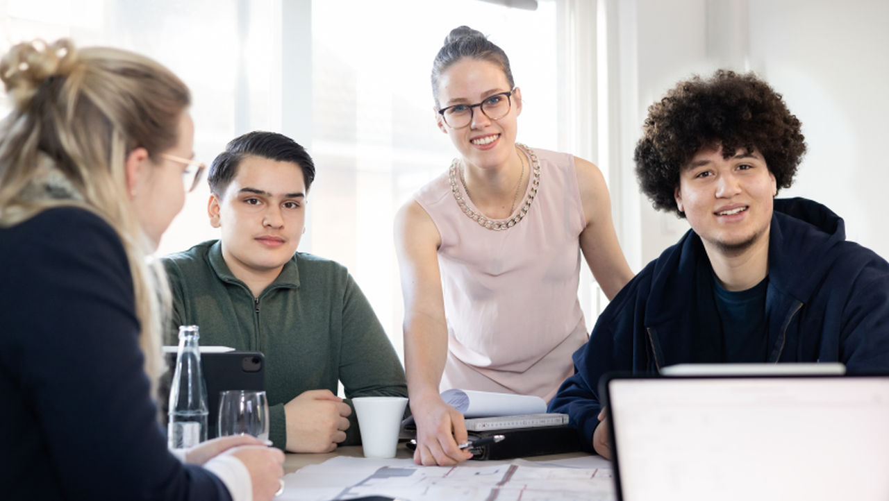 Gruppe junger Menschen bei Zusammenarbeit an einem Schreibtisch