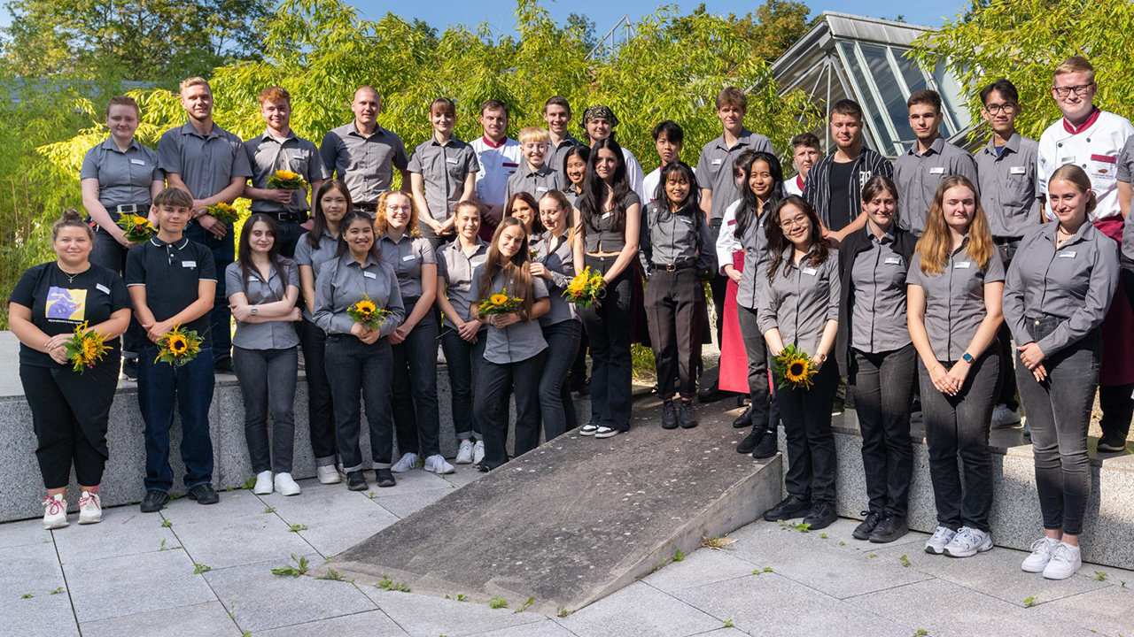 Gruppenbild, einige Personen mit Blumensträußen
