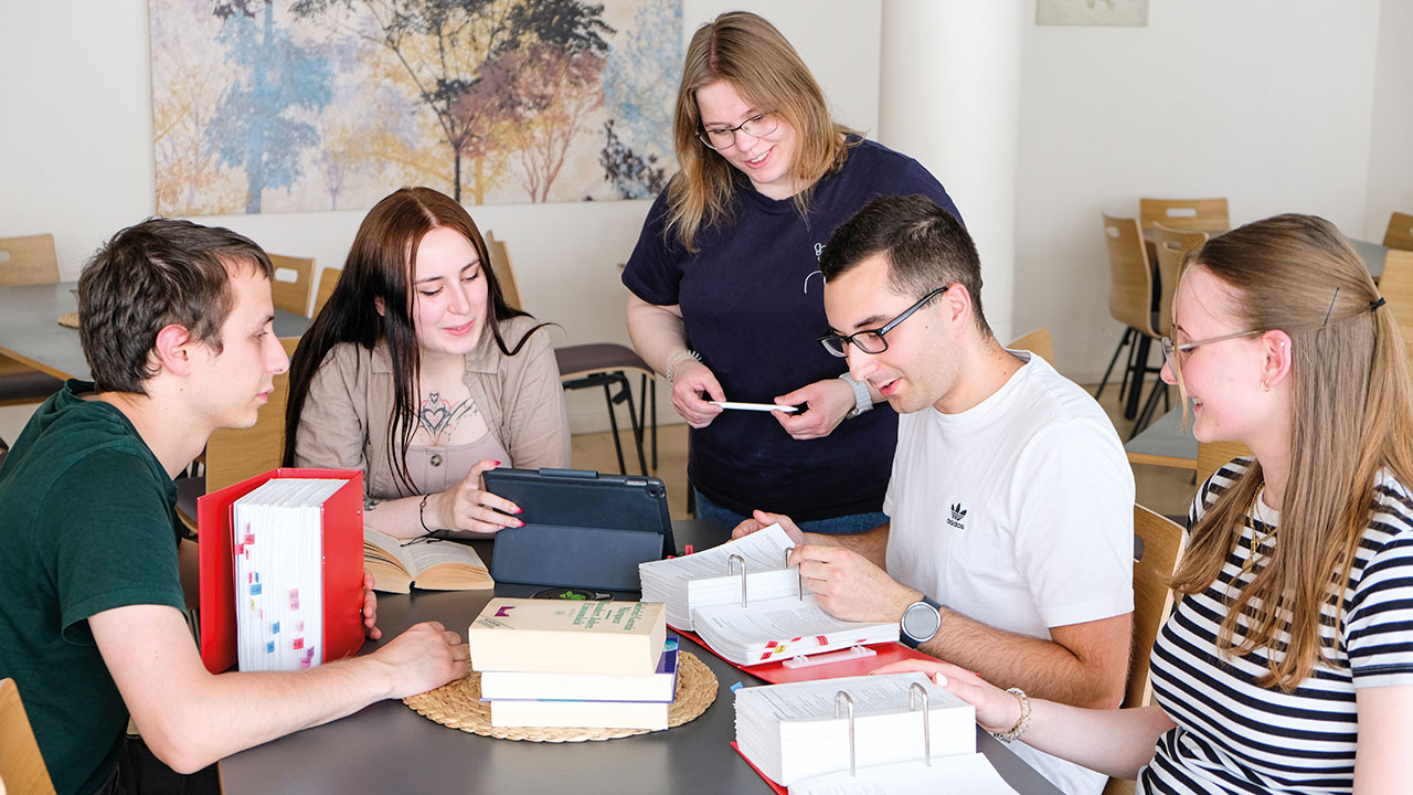 Junge Menschen mit Büchern an einem Tisch