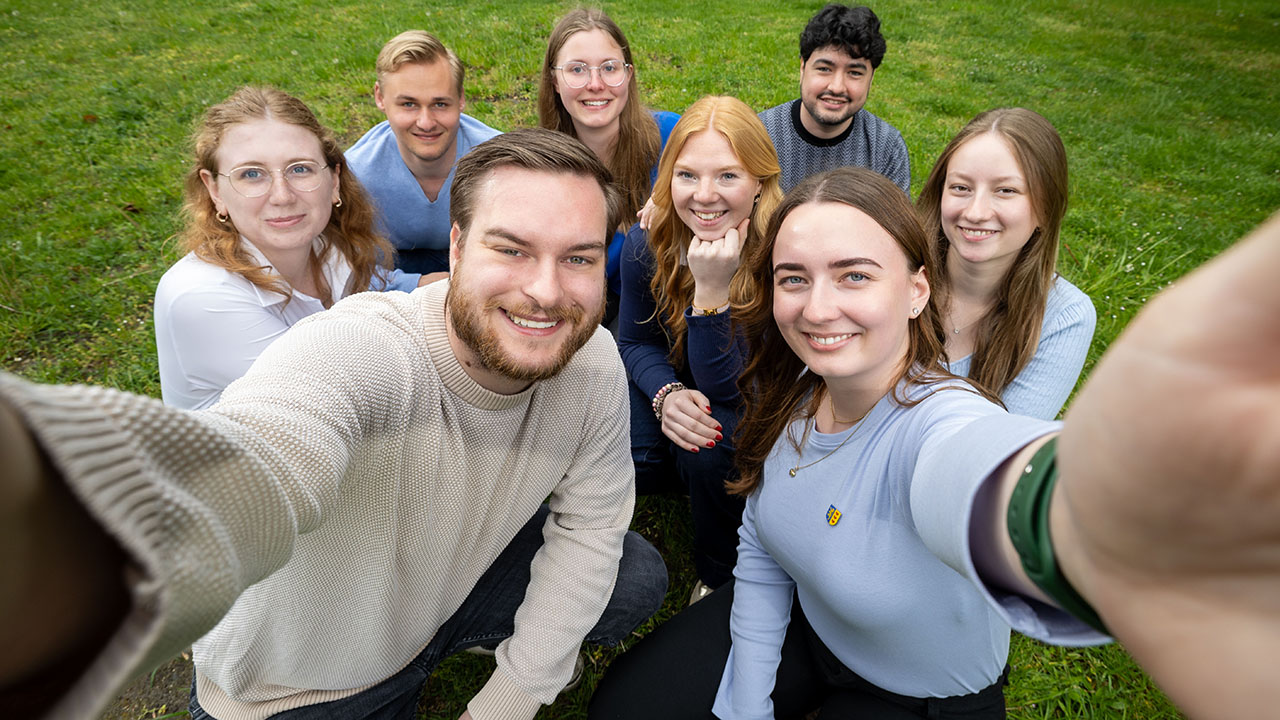 Selfie von acht jungen Menschen, die in die Kamera lächeln