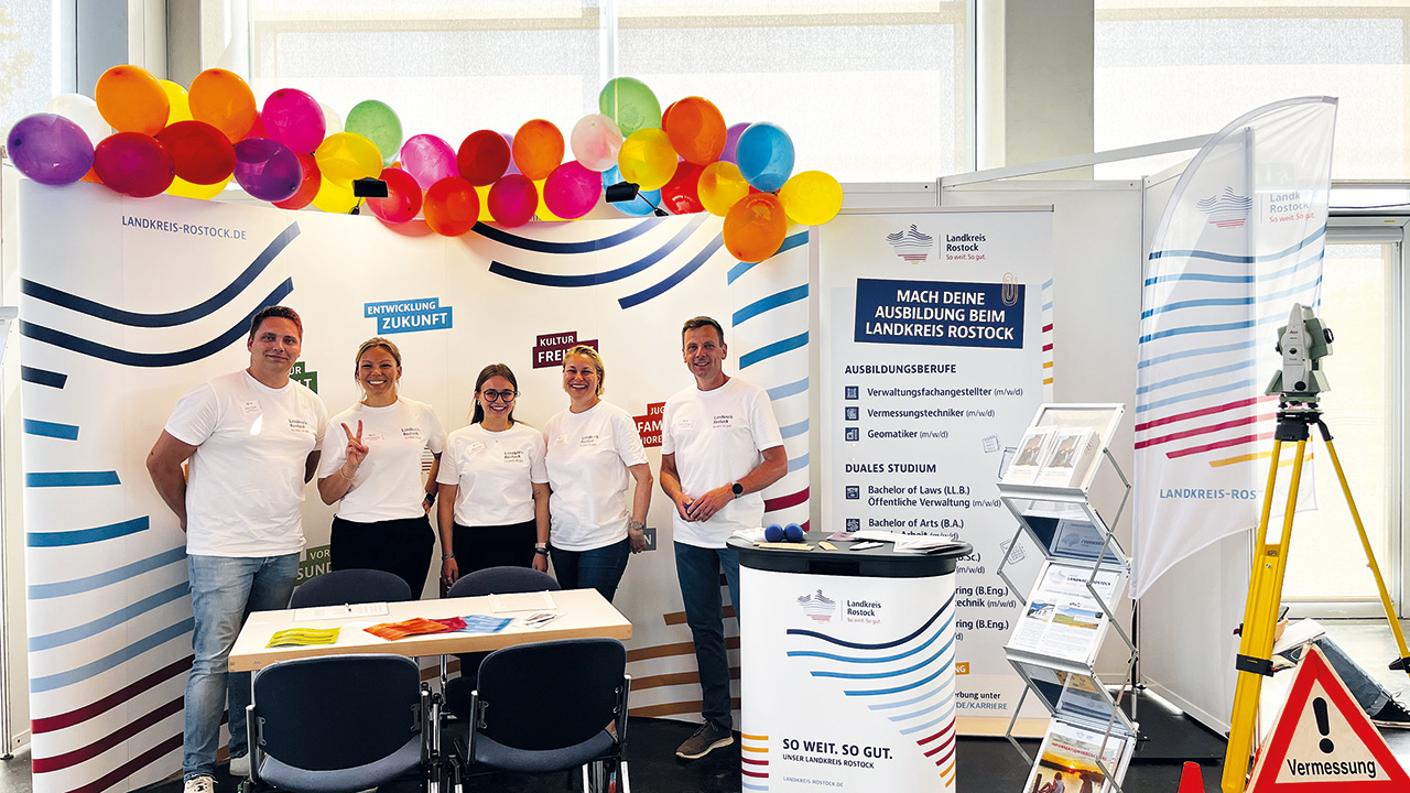 Gruppenbild am MEssestand mit bunten Luftballons