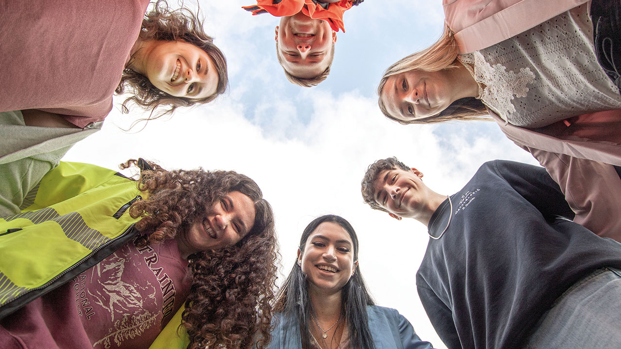 Sechs Personen blicken nach unten in eine Kamera und lächeln.