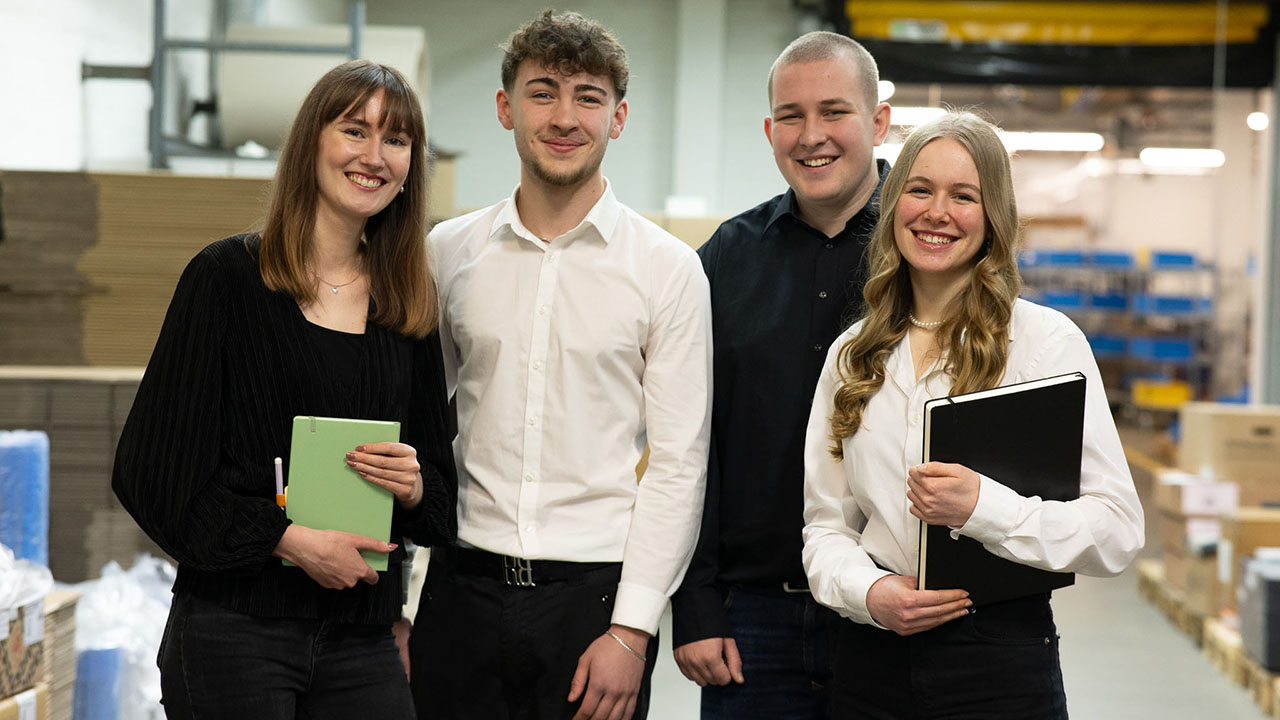 Vier junge Menschen in Businesskleidung lächeln in die Kamera
