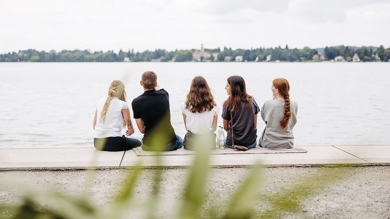 Gruppe junger Menschen sitzt am Bodensee