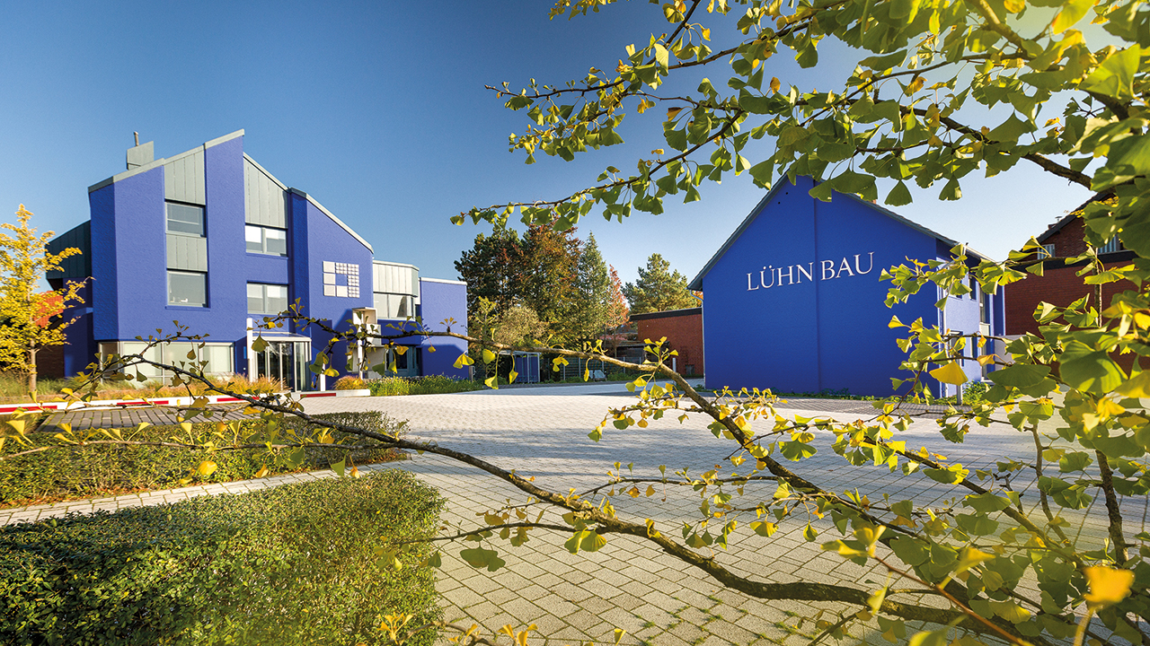2 blaue Gebäude in der Natur, auf einem steht "Lühn Bau"
