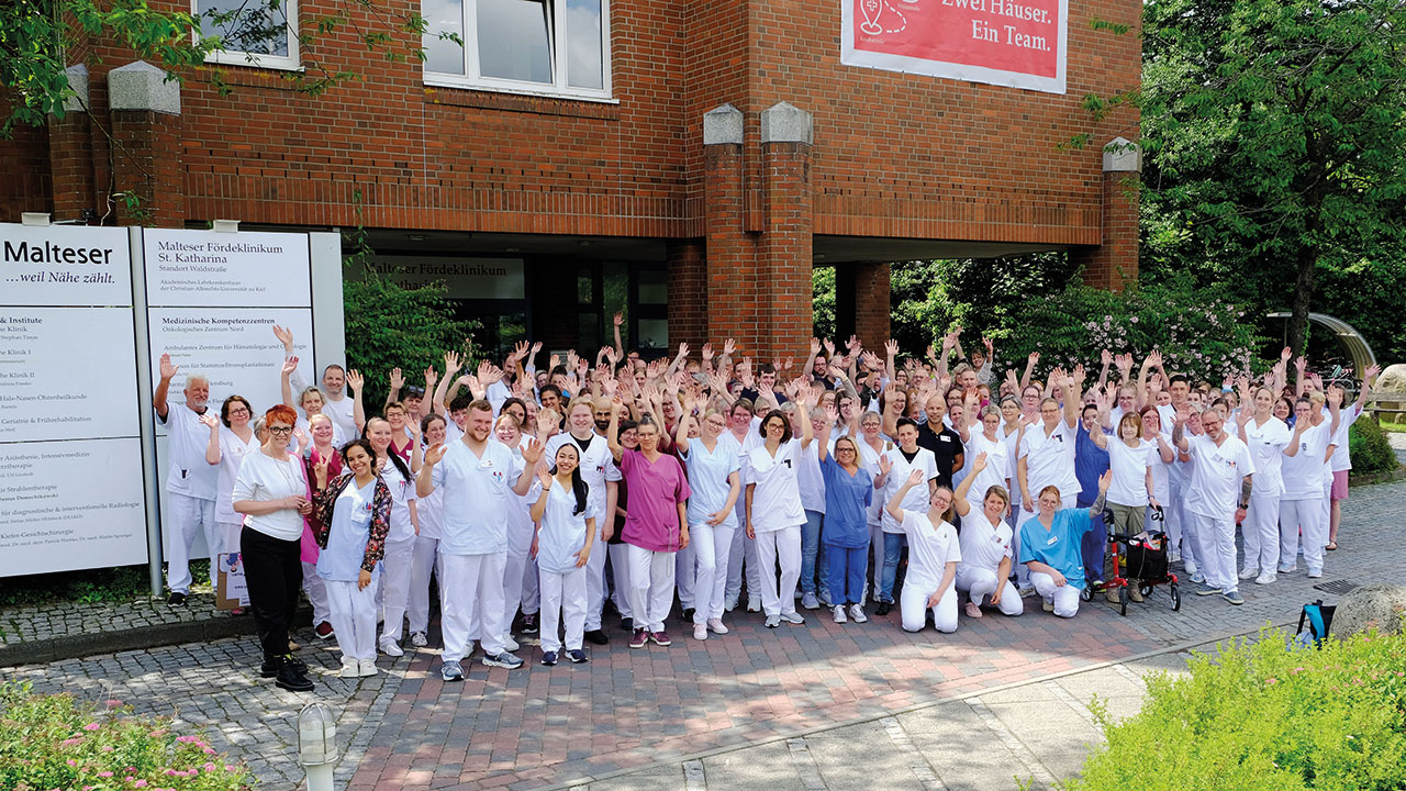 Gruppe der Mitarbeitenden des Malteser Fördeklinikum St. Katharina vor dem Krankenhaus als Gruppenbild