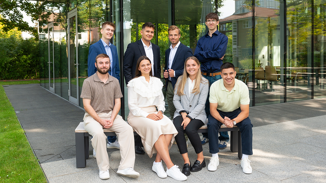Gruppenbild mit 8 jungen Menschen vor dem modernen Firmengebäude