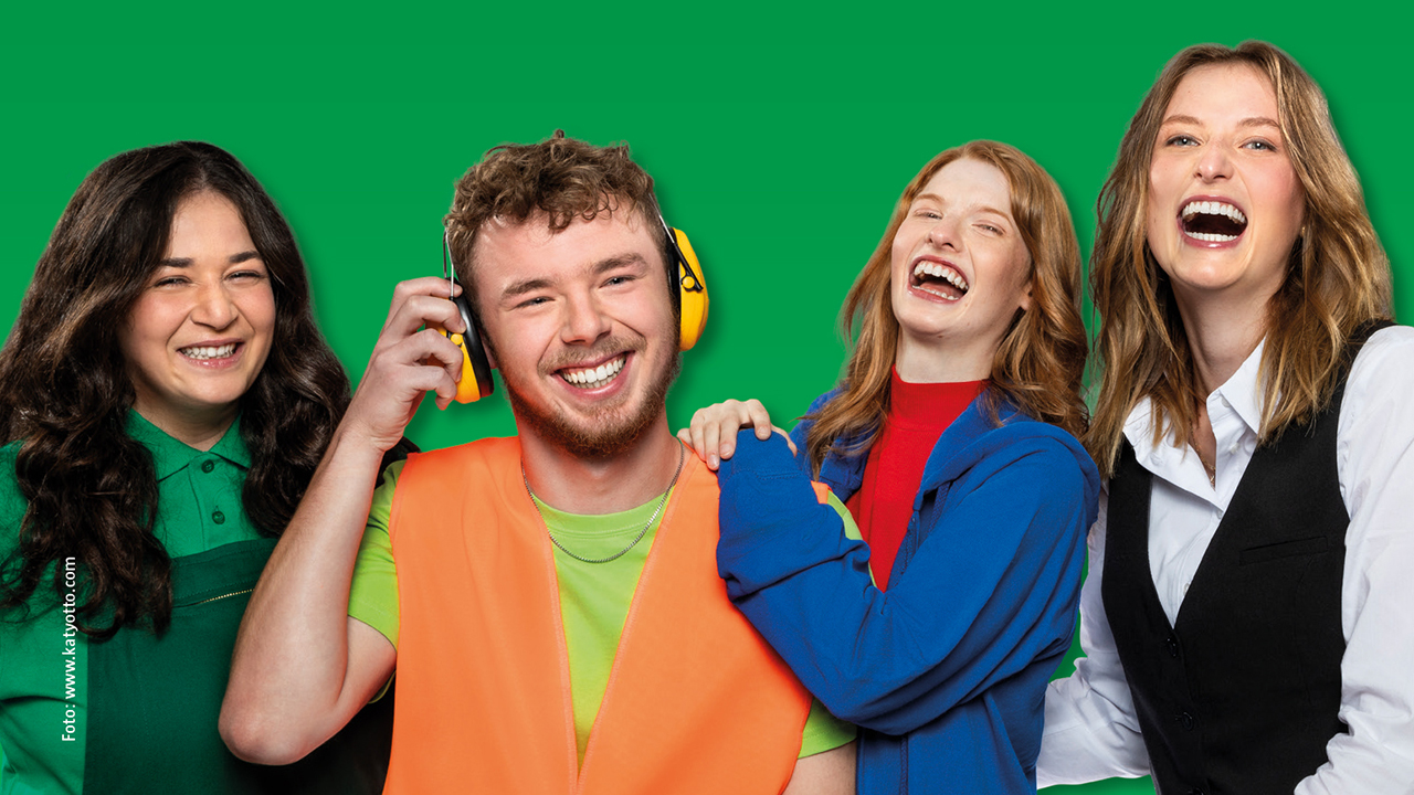 Gruppe junger Menschen vor grünem Hintergrund, alle lachen in die Kamera