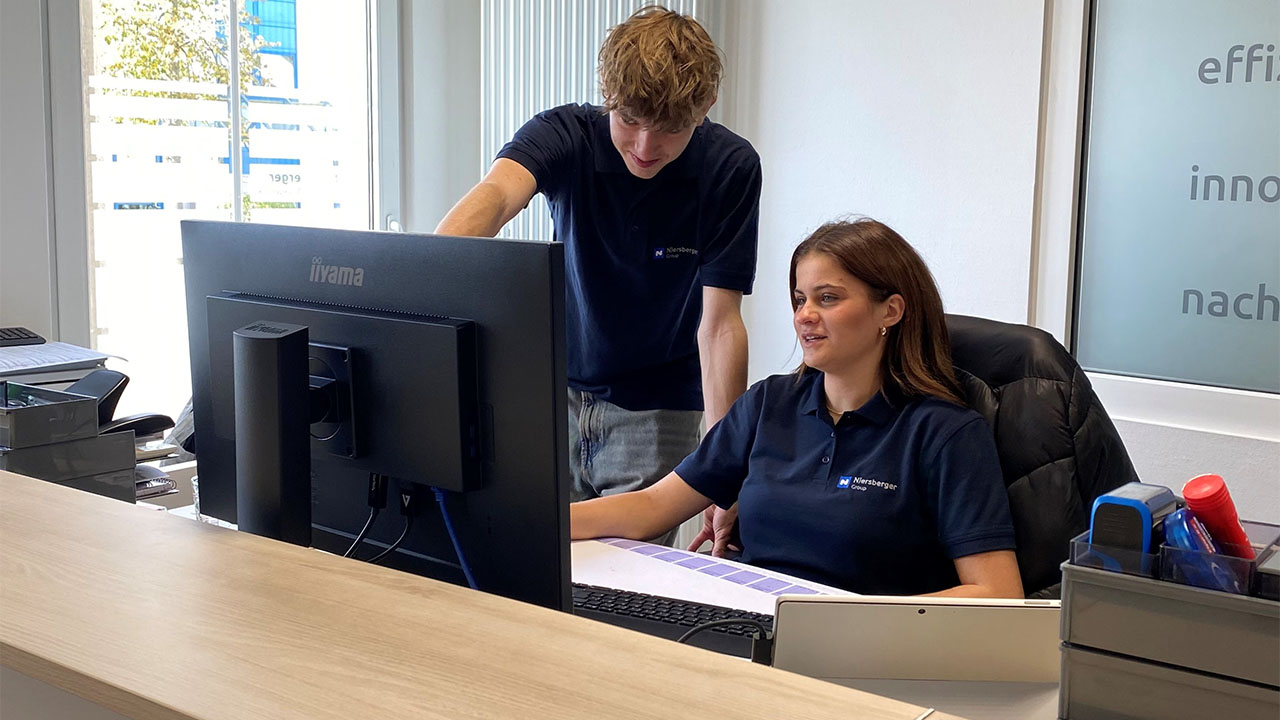 Zwei Personen vor einem Computer.