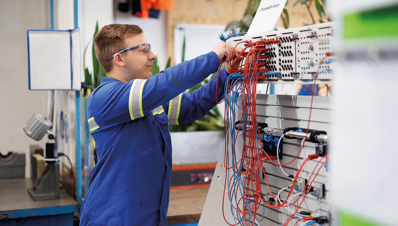 Junger Mann steckt elektronische Verbindungen in einer Lehrwerkstatt.