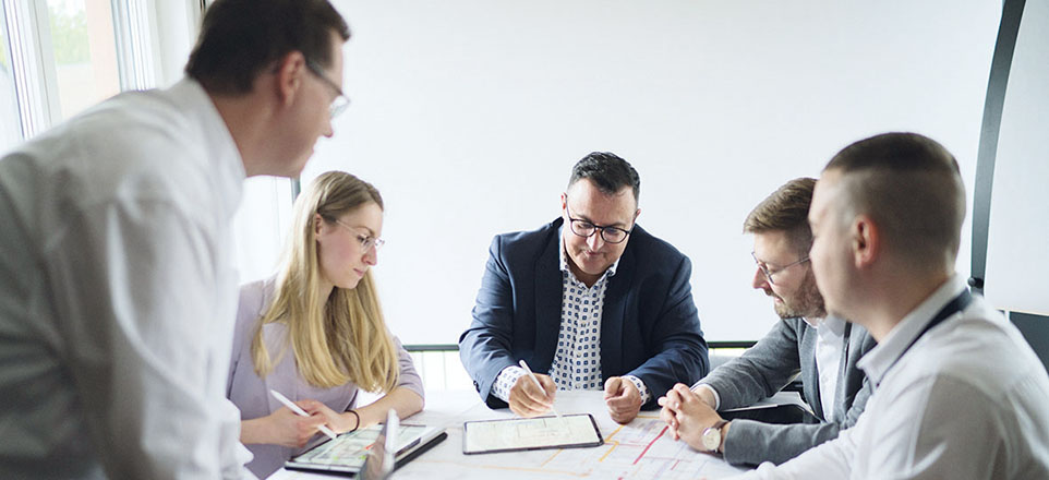 Fünf Mitarbeitende der pi Passau Ingenieure GmbH in einer Besprechung