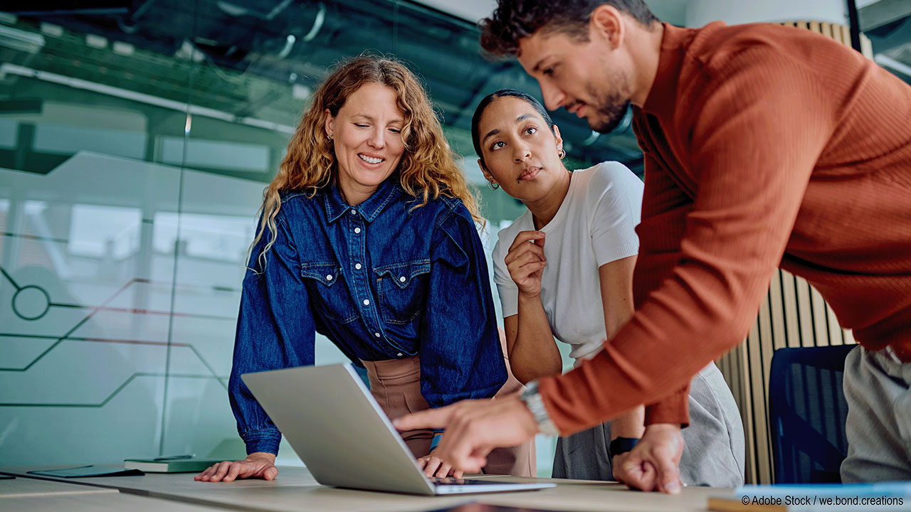 Person zeigt zwei anderen Personen etwas am Laptop