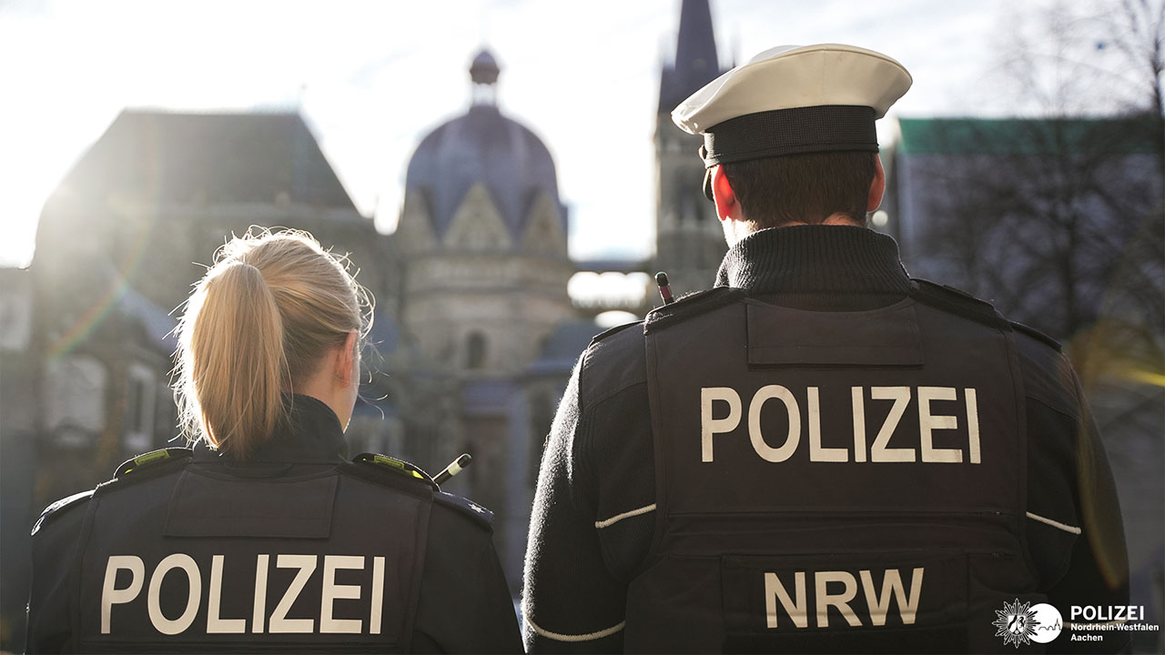 Rückenansicht von zwei Polizisten, im Hintergrund steht der Dom.