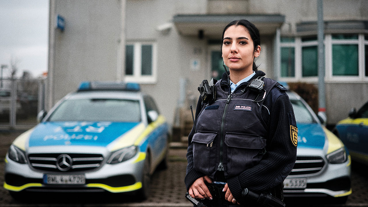 Polizistin in Uniform vor Einsatzwagen