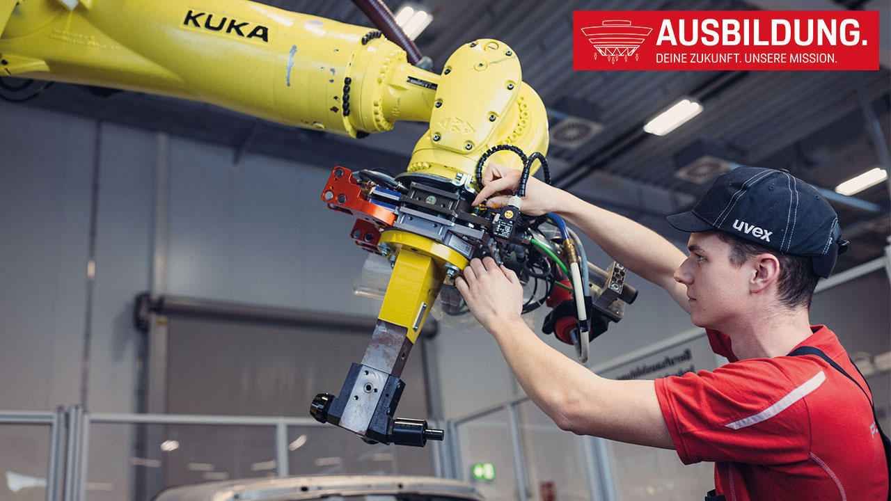 Junger Mitarbeitender arbeitet mit Roboterarm