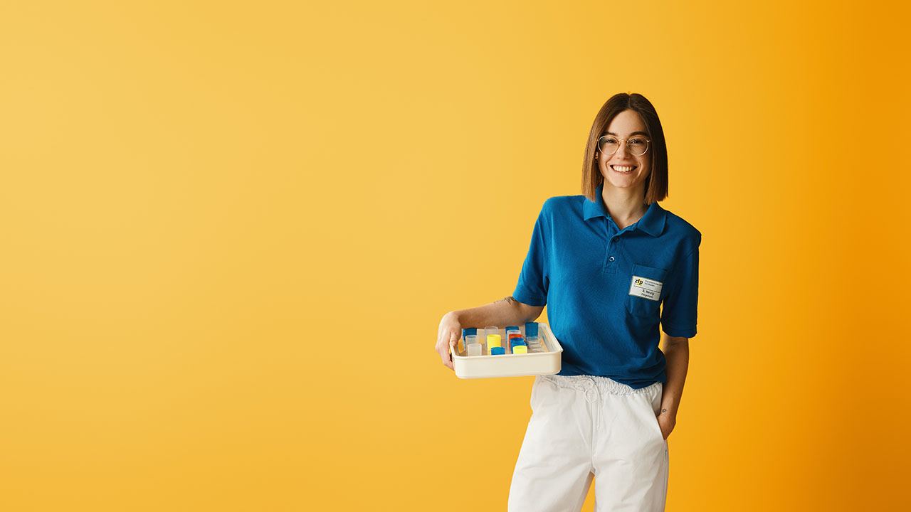 Person mit einem Tablett in der Hand vor einem orangenem Hintergrund.