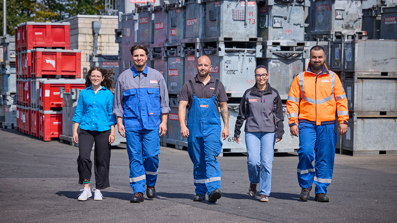 Gruppe junger Mitarbeitender gehen in Arbeitskleidung auf Kamera zu
