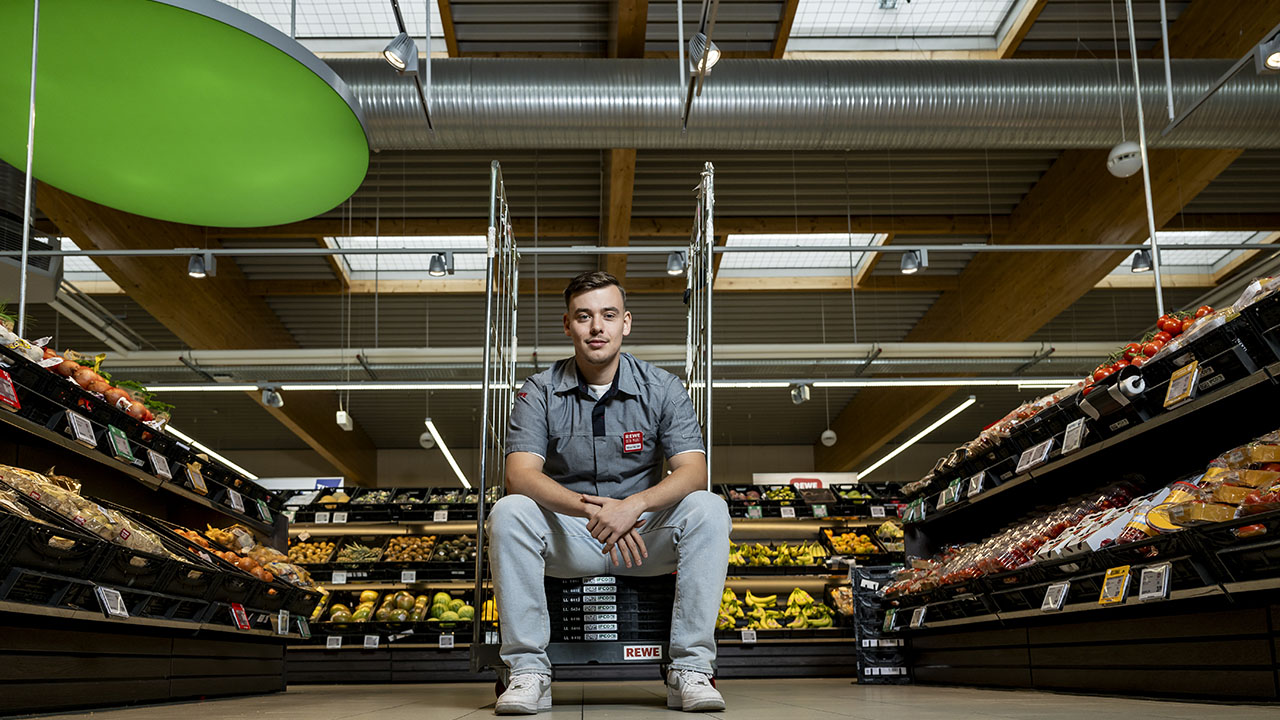 Person sitzt in einem REWE-Markt.