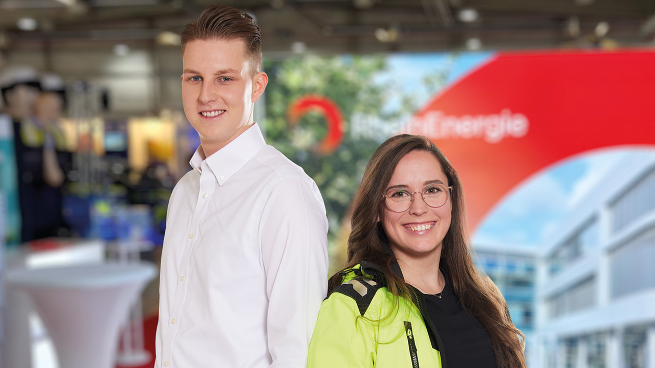 Zwei junge Mitarbeitende lächeln in die Kamera