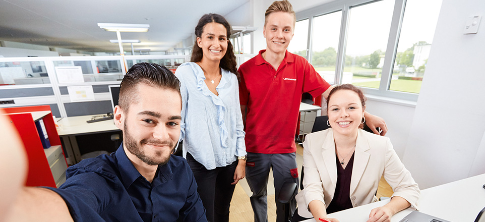 Vier Personen sitzen in einem Büro und machen ein Selfie.