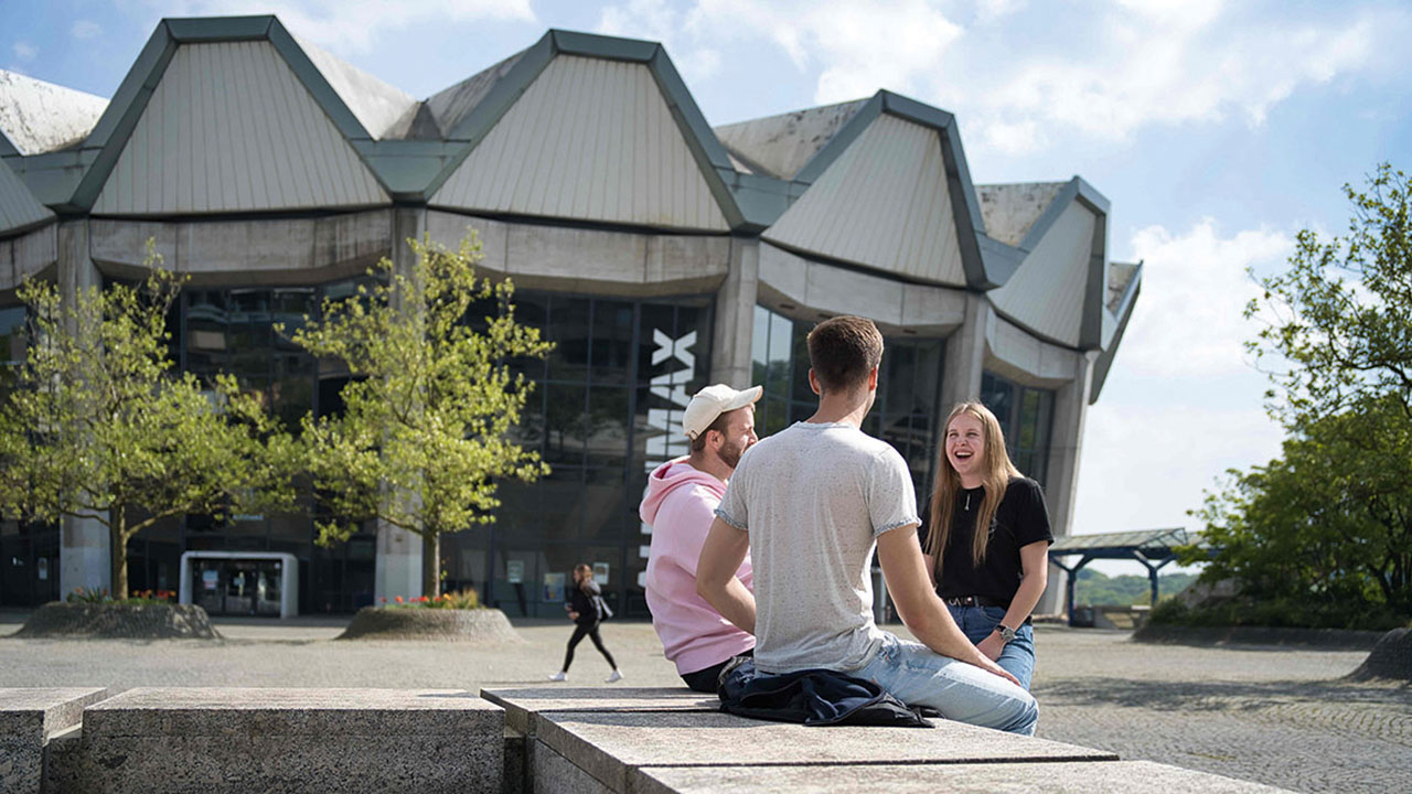 Drei Studierende vor dem Gebäude der Ruhr-Universität Bochum
