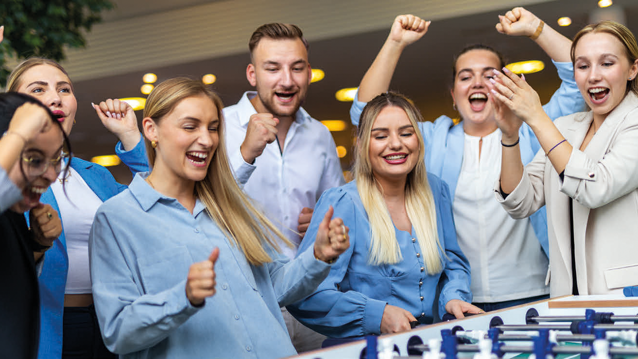 Mehrere junge begeisterte Menschen beim Tischkicker-Spiel
