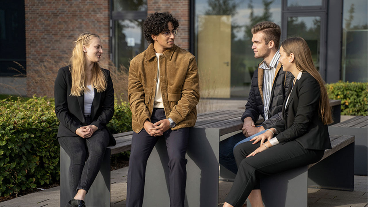 Vier junge Menschen im Gespräch vor einem Gebäude