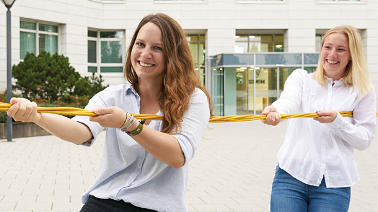 Zwei Frauen ziehen an einem Seil. 