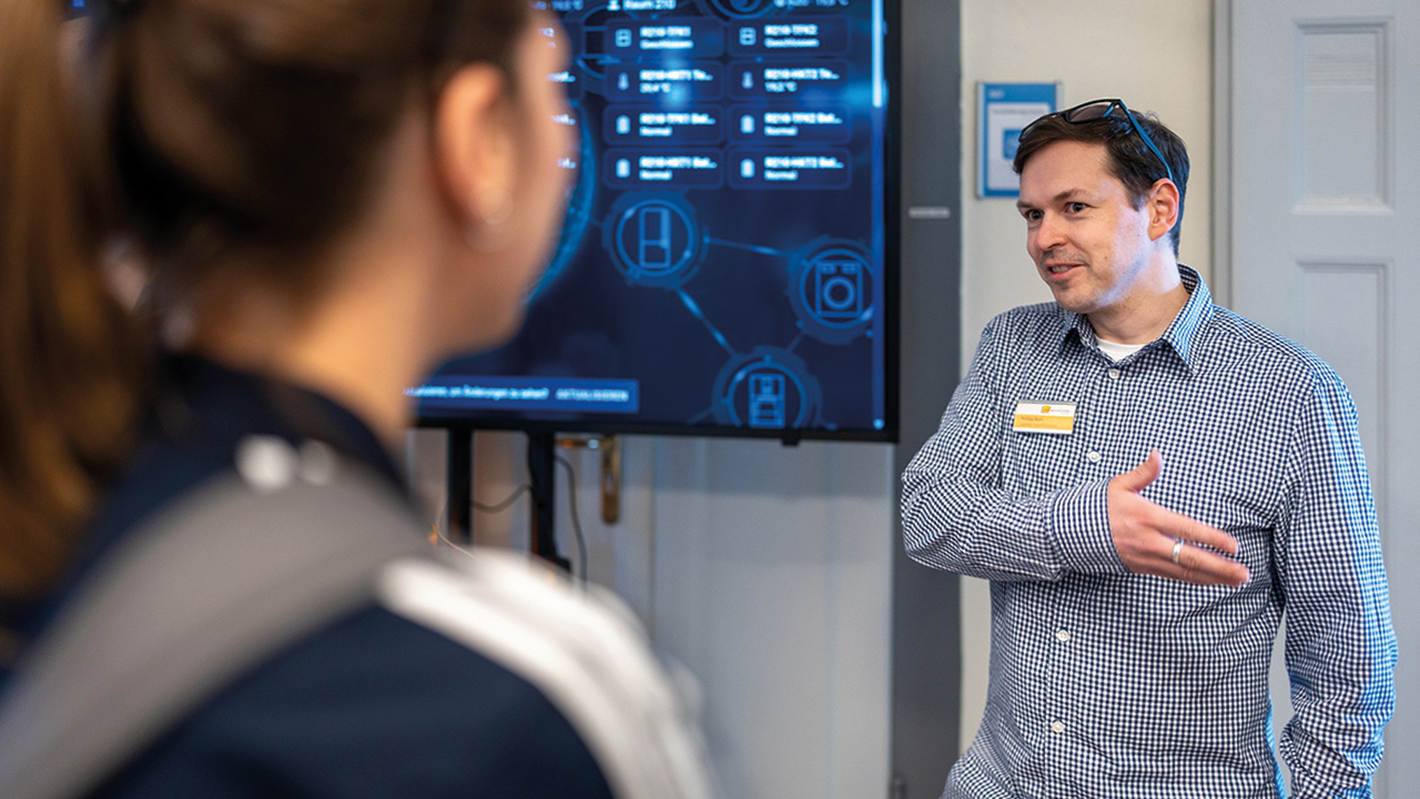 Lehrender vor einer digitalen Tafel, der gerade etwas erklärt. 