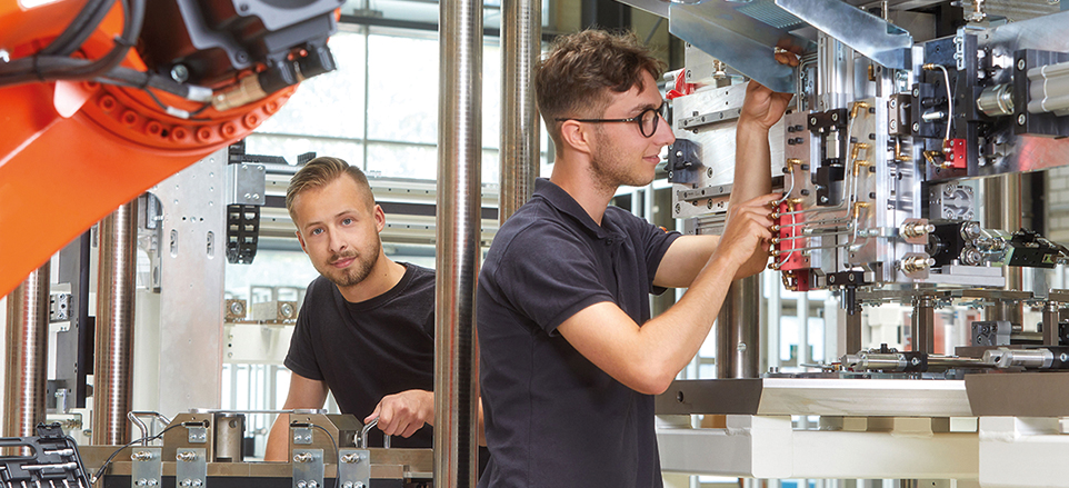 Zwei junge Männer bei der Arbeit an technischen Geräten in einer Werkstatt
