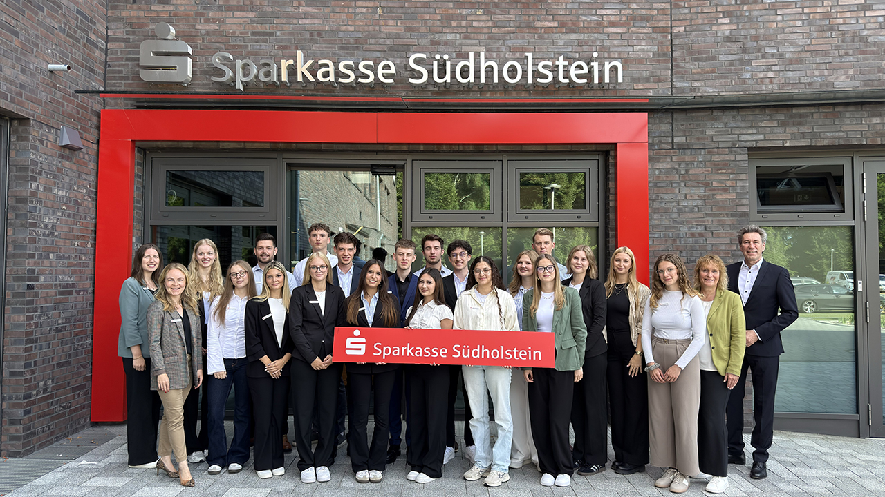 Das Bild zeigt eine Menschengruppe vor einer Filiale der Sparkasse Südholstein. 