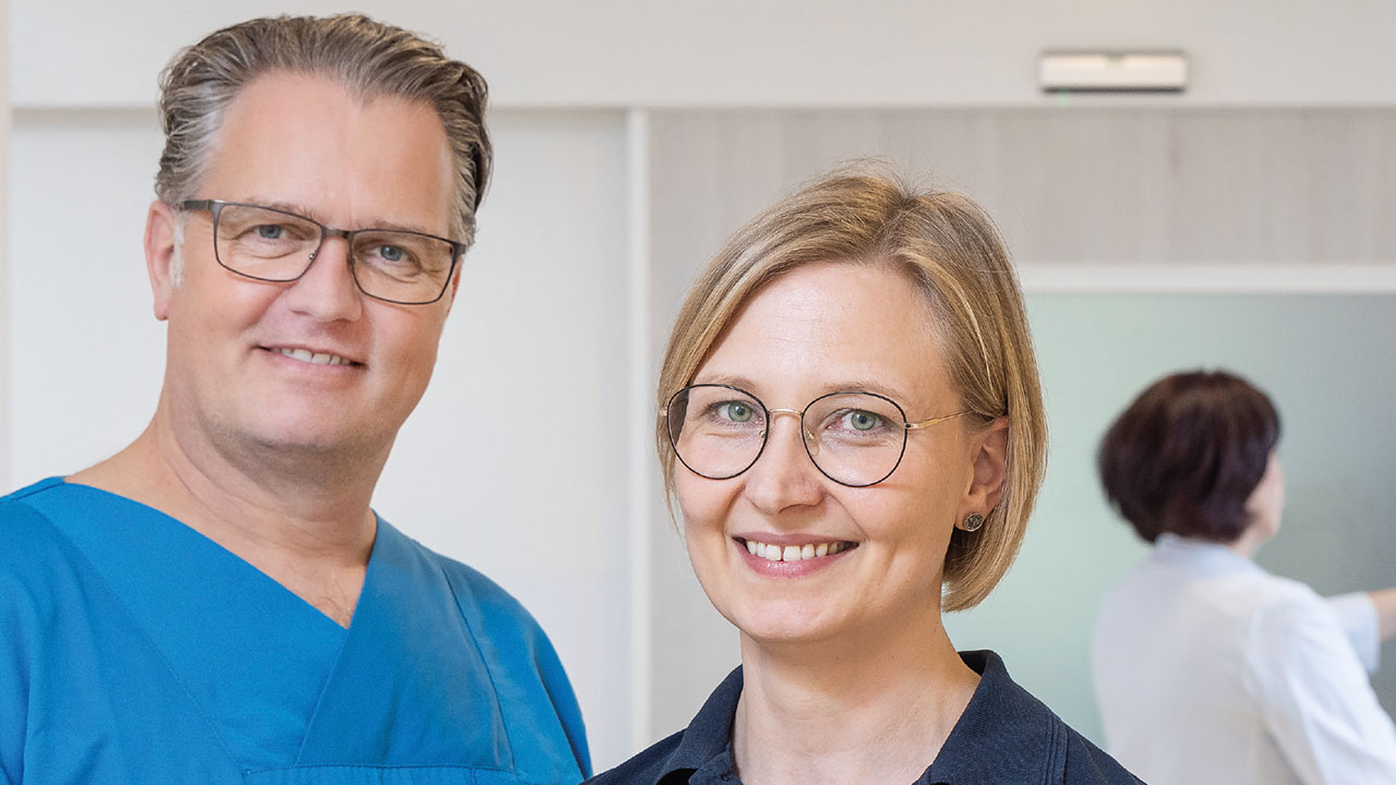 Zwei Personen in einem krankenhaus lächeln in die Kamera.