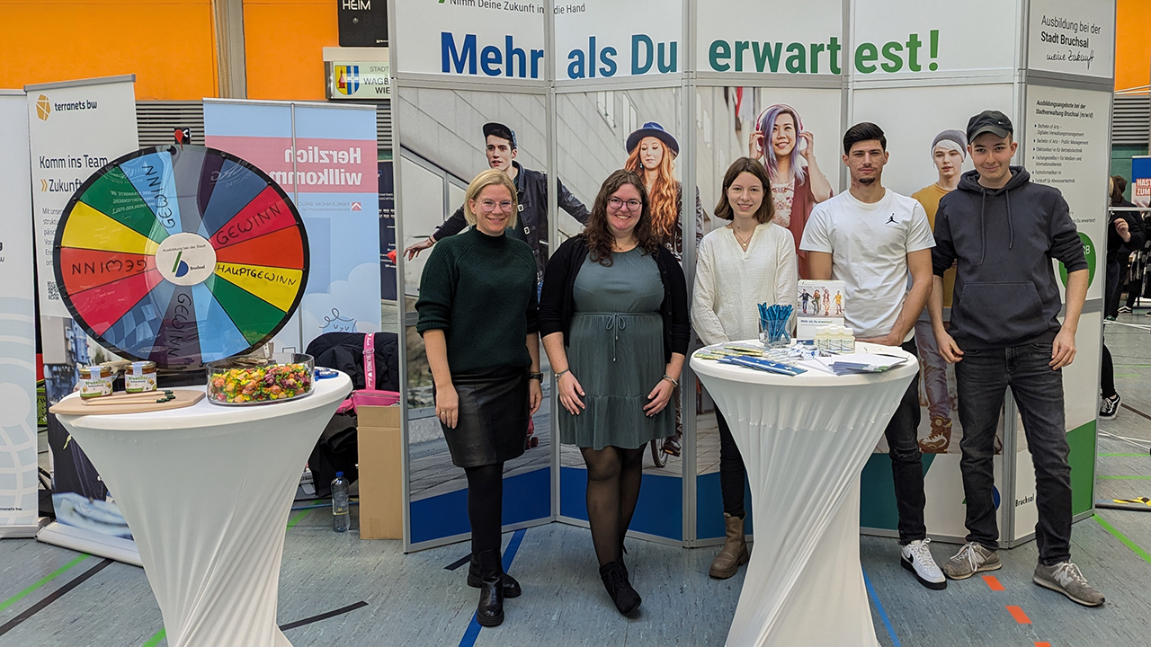 Das Bild zeigt mehrere Personen an einem Messestand. 