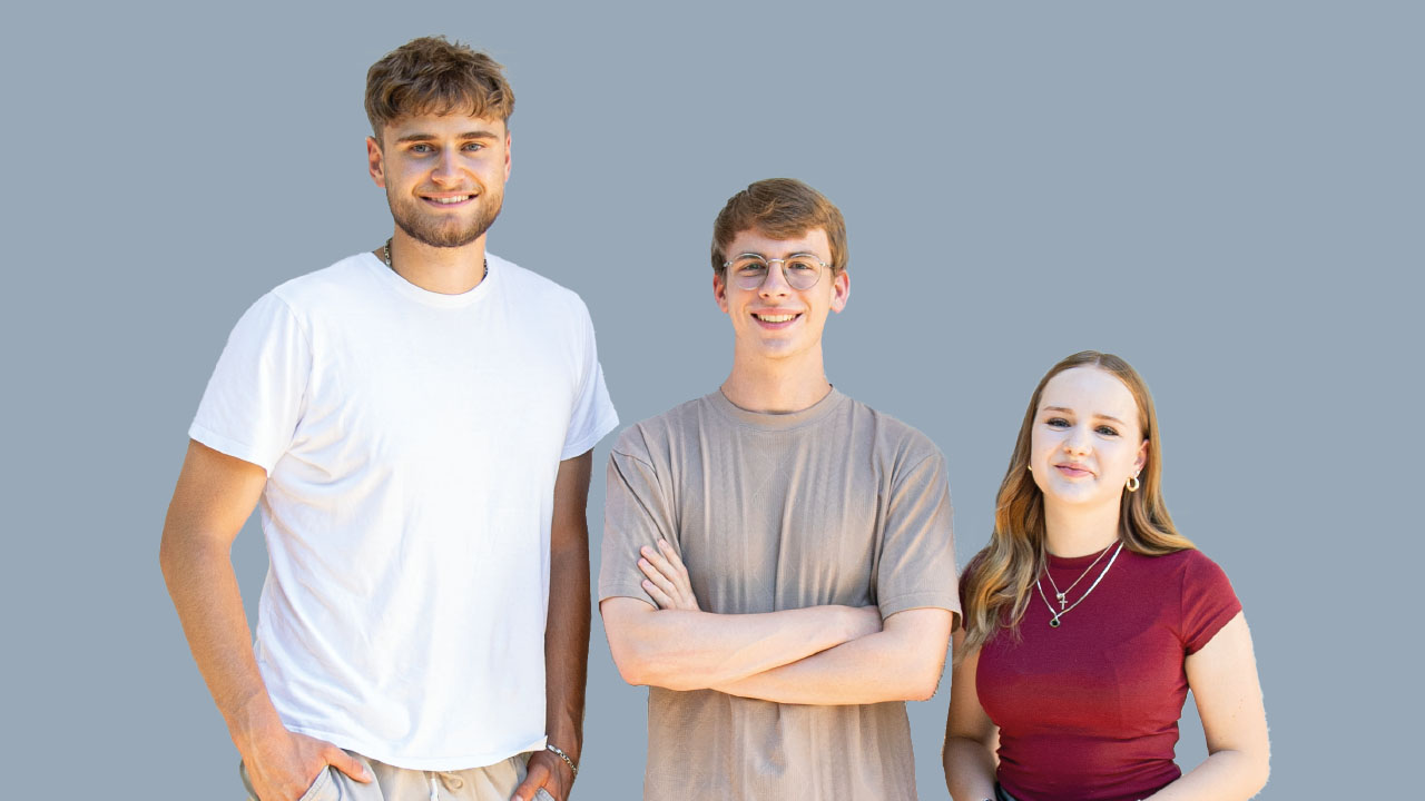 Drei Personen vor grauem Hintergrund sehen in die Kamera und lächeln.