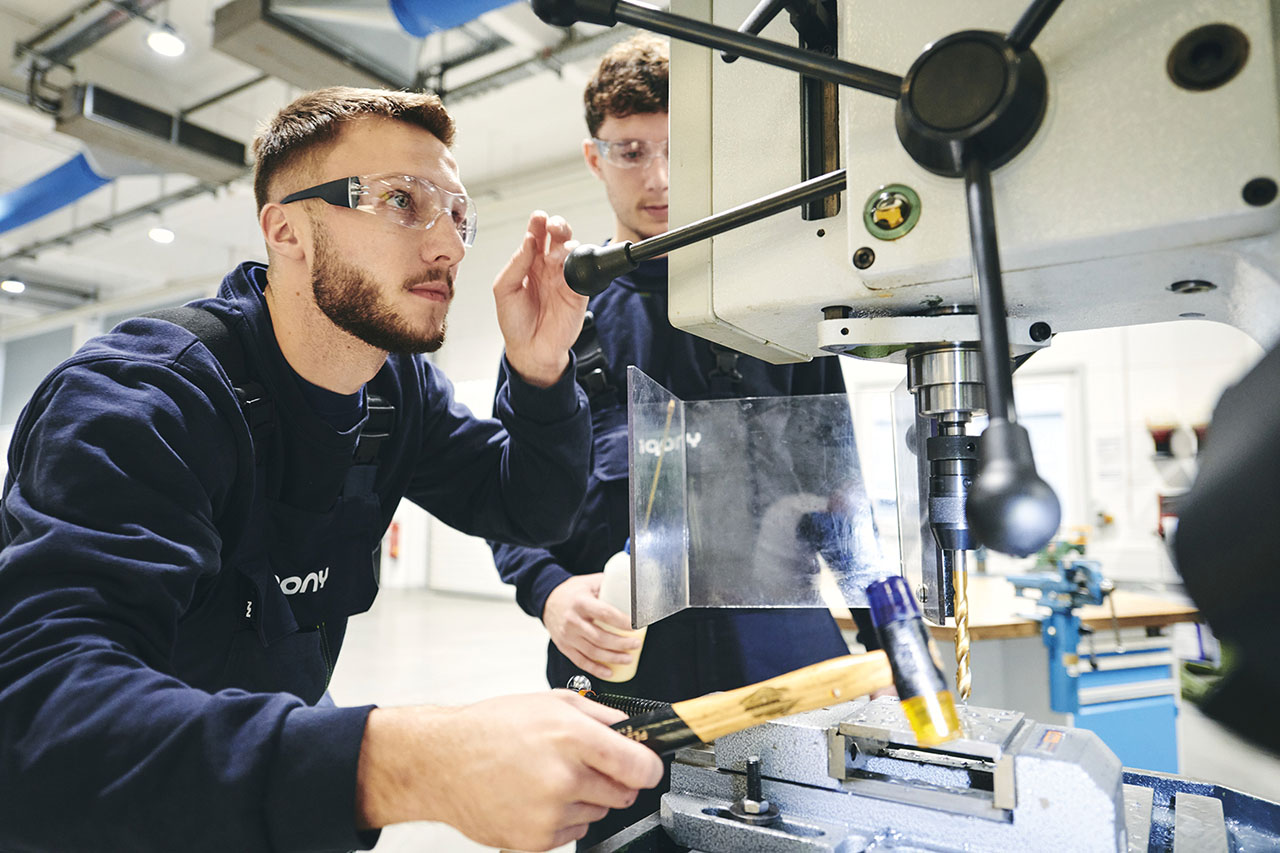 Junger Mann mit Schutzbrille arbeitet an einer Maschine