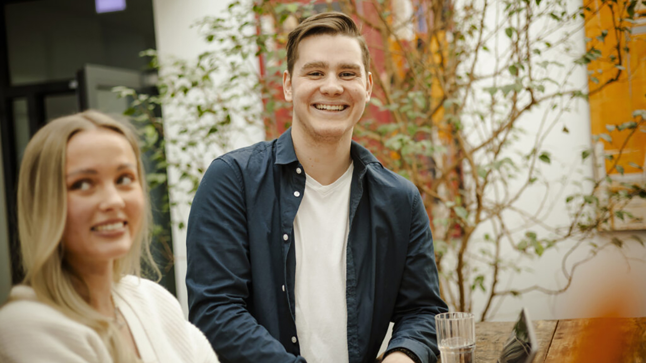 Das Bild zeigt zwei Personen die in die Kamera blicken und lächeln.