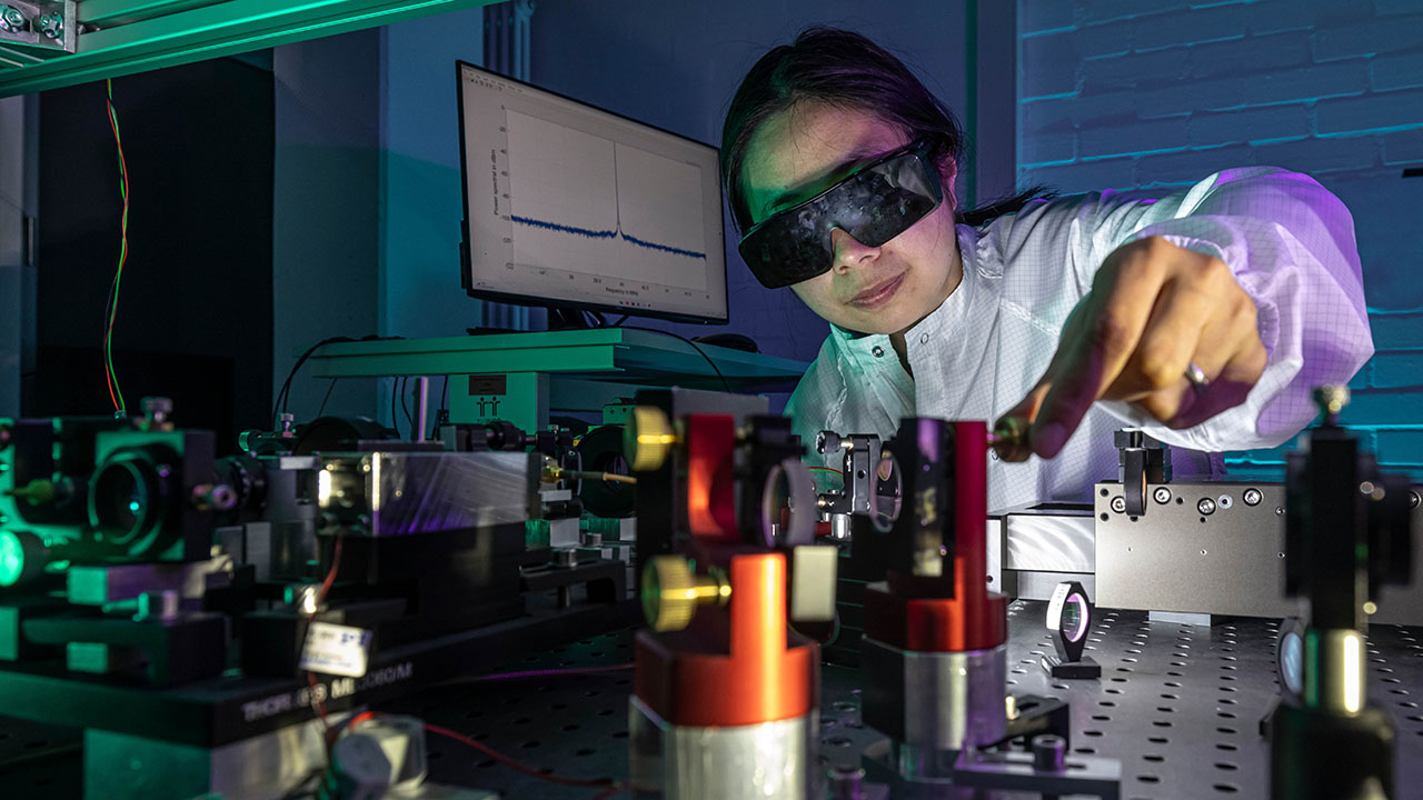 Person in Schutzkleidung mit Schutzbrille arbeitet mit einem Laser im Labor