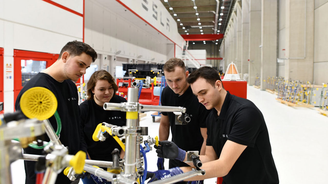 Vier Auszubildende in schwarzen T-Shirts in der Produktionsstätte