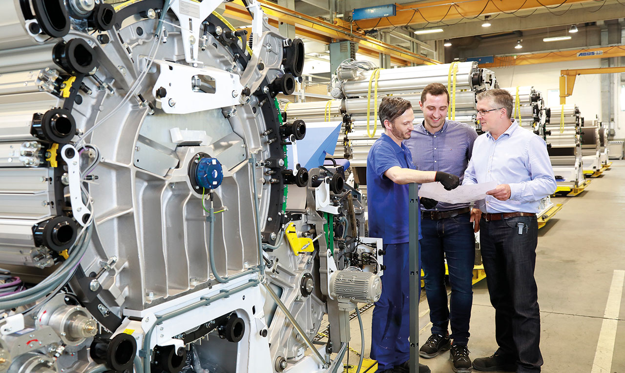 Personen im Gespräch vor einer großen Maschine