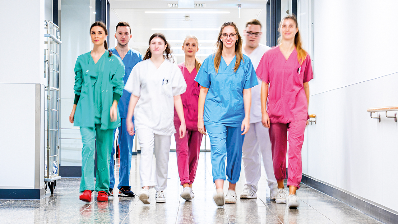 Junge Angestellte verschiedener Berufsgruppen der Klinilk kommen in der Gruppe auf die Kamera zu